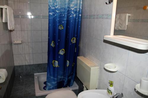 a bathroom with a blue shower curtain with fish on it at Apartments Milena & Ante in Makarska