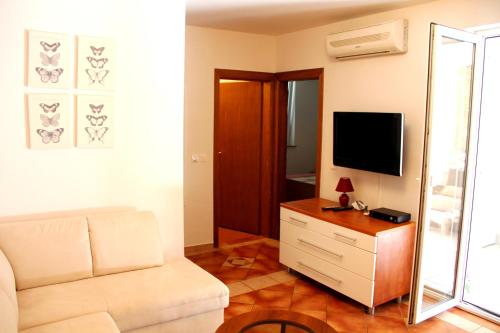 uma sala de estar com um sofá branco e uma televisão em Green Paradise Apartment Novalja em Novalja