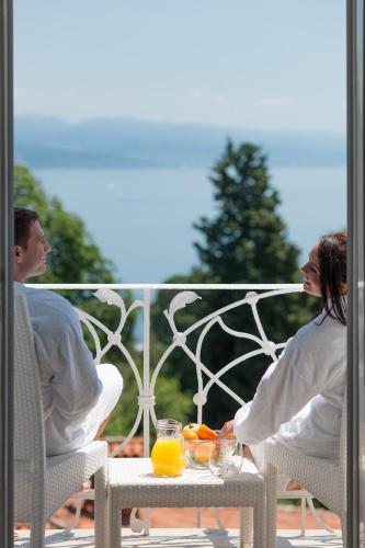 two people sitting on a porch with oranges on a table at BRISTOL Hotel Opatija in Opatija