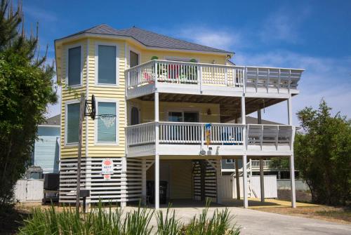 a large yellow house with a white deck at Shore Is Fun in Duck