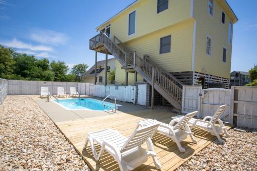 a backyard with a pool and chairs and a house at Shore Is Fun in Duck