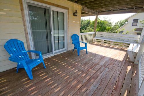 two blue chairs on a porch with a bench at Shore Is Fun in Duck