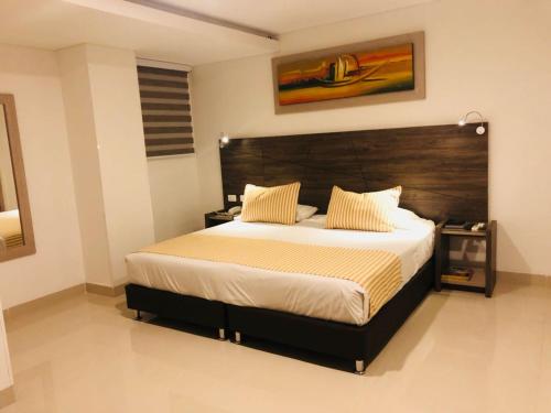 a bedroom with a large bed with a wooden headboard at Hotel Toscana Plaza in Cali