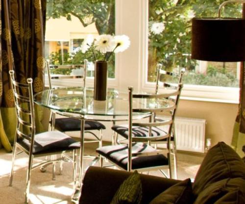 un tavolo in vetro con sedie e un vaso con fiori di Harrogate Boutique Apartments - Self Contained Apartments a Harrogate