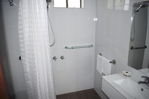 a white bathroom with a shower and a sink at Healesville Motor Inn in Healesville