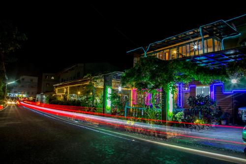 a building with colorful lights on a street at night at Rui Li Yinxiang Qu Homestay in Meishan
