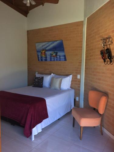 a bedroom with a large bed and a chair at Villa Cottage Pousada in Monte Alegre do Sul