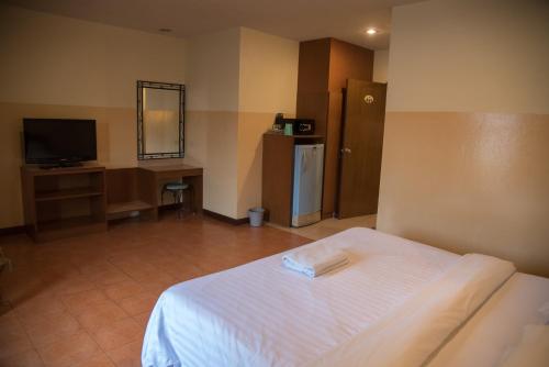 a hotel room with a bed and a television at Opey De Place in Pattaya