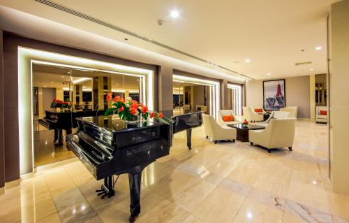 a room with a piano and a living room with a table and chairs at Mandarin Hotel Managed by Centre Point in Bangkok