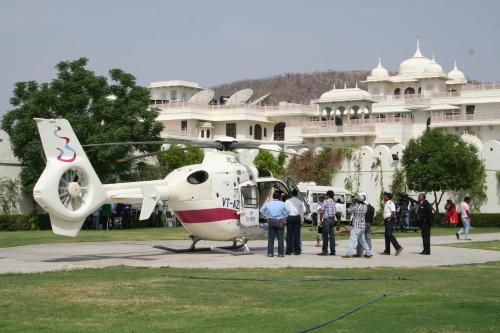 a group of people standing next to a helicopter in front of a building at Shiv Vilas Resort in Jaipur