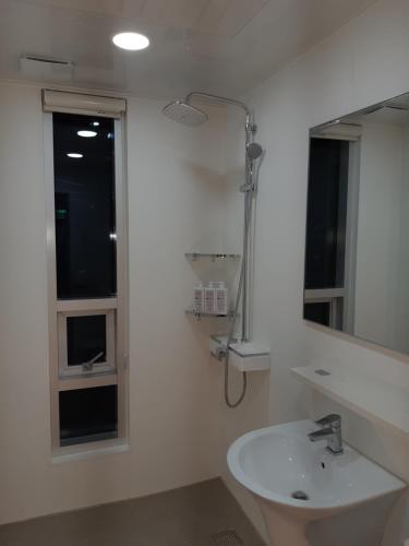 a white bathroom with a sink and a mirror at For You Hostel in Yeosu