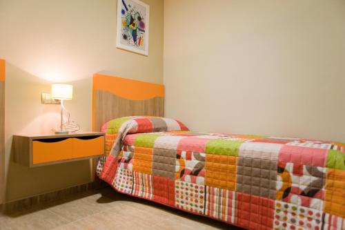 a bedroom with two beds and a table with a lamp at Hotel y Apartamentos Conilsol in Conil de la Frontera