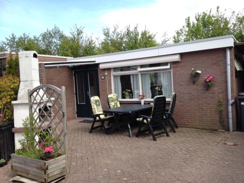 a patio with a black table and chairs in front of a building at De Vlinder Renesse in Renesse