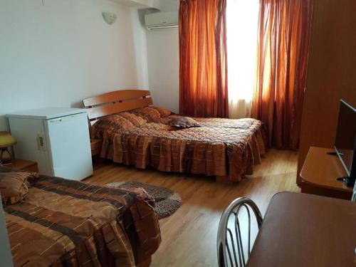 Cette chambre comprend deux lits, une table et un bureau. dans l'établissement Hotel Floare de Colt, à Teiuş