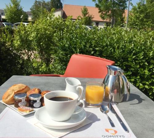 een kop koffie en een bord eten op een tafel bij Domitys Le Côteau d'Argent in Saint-Doulchard