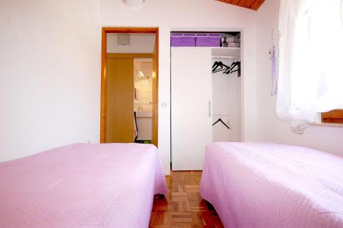 two beds in a room with white sheets at Apartment Bedenikovic in Malinska