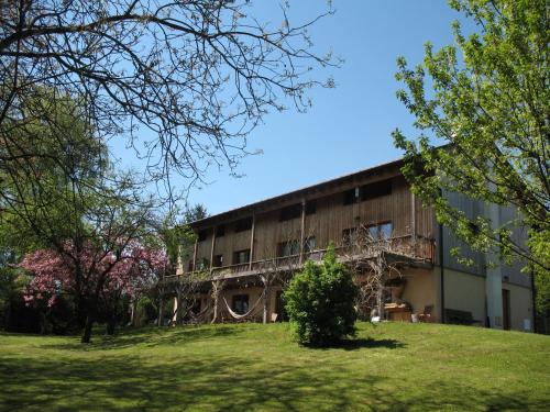 a building on a hill with trees in the foreground at BioAgriturismo Vegan Campo di Cielo in Cesiomaggiore