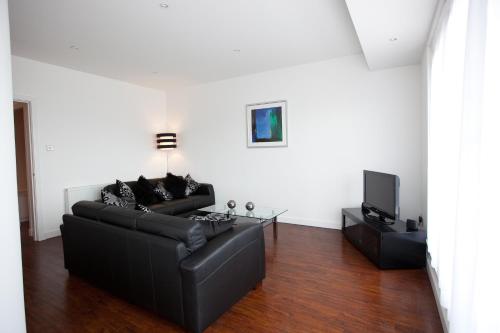 a living room with a black couch and a tv at The Spires Serviced Apartments Glasgow in Glasgow
