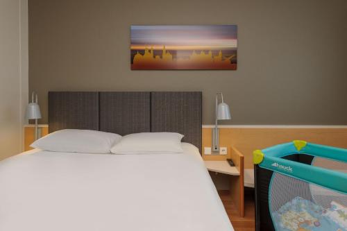 a bedroom with a bed and a picture on the wall at ibis Hotel Würzburg City in Würzburg