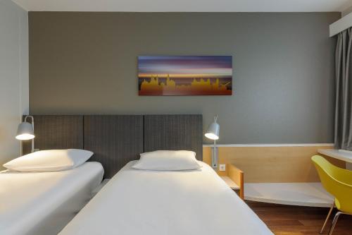 a hotel room with two beds and a desk at ibis Hotel Würzburg City in Würzburg