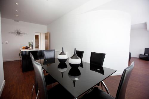 a black dining room table with chairs and vases on it at The Spires Serviced Apartments Glasgow in Glasgow