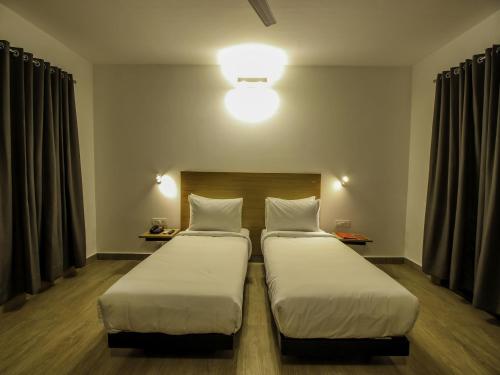 two twin beds in a room with a light at Oceans 7 Ashwem in Mandrem