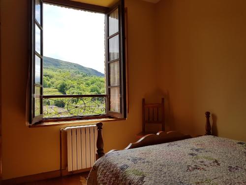 1 dormitorio con cama y ventana con vistas en Apartamentos Rurales La Escuela, en Buelles