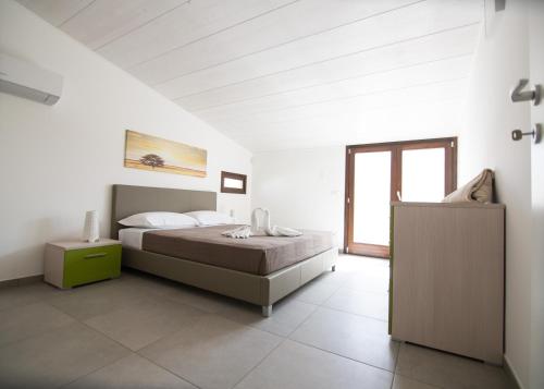 a white bedroom with a bed and a window at Ville Edilia Vacanze in Marina di Ragusa