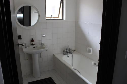 a bathroom with a sink and a bath tub and a mirror at Durban Holiday House in Durban