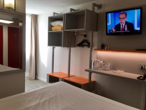 a room with a tv on the wall and a bed at Hotel du Parc Euromédecine by AKENA in Montpellier