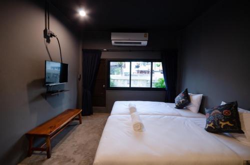 a room with two beds and a tv and a window at Tian Tian Hostel in Bangkok