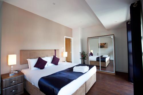 una camera da letto con un grande letto e un grande specchio di The Spires Serviced Apartments Glasgow a Glasgow