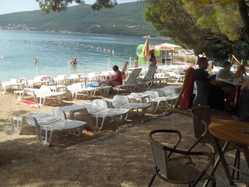 a group of people sitting in chairs on a beach at Apartments Colic in Herceg-Novi