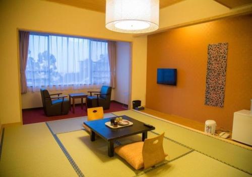 a living room with a table and a dining room at Higashiyama Park Hotel Shinfugetsu in Aizuwakamatsu