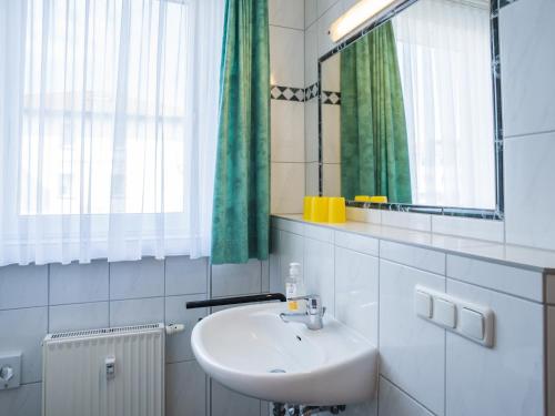 een badkamer met een wastafel, een spiegel en groene gordijnen bij Ferienhaus am Maiglöchchenberg 5 in Ostseebad Karlshagen