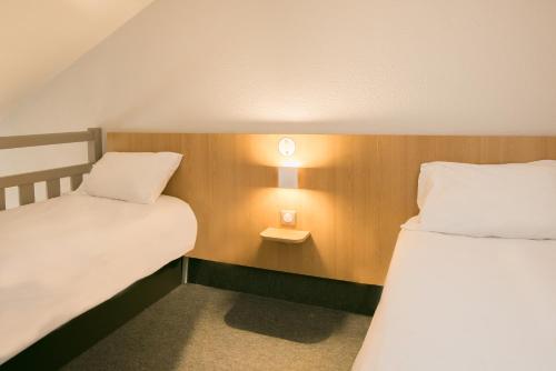 a room with two beds and a light on the wall at B&B HOTEL Nantes Parc Expos La Beaujoire in Nantes
