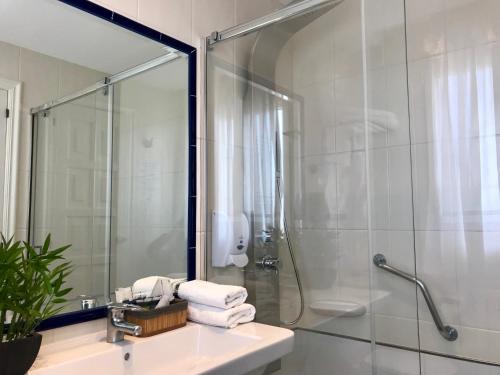 a bathroom with a shower and a sink and a mirror at Hotel Nuevo Vichona Spa 3 estrellas Superior in Sanxenxo
