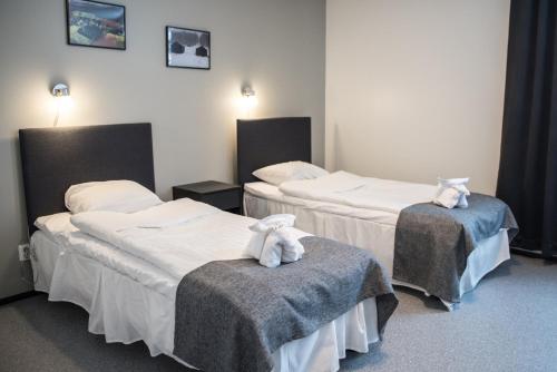 two beds in a hotel room with towels on them at Hotelli Kampeli in Veteli