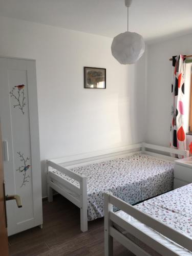 een witte slaapkamer met 2 bedden en een hanglamp bij Apartment Ružmarin Porat in Porat