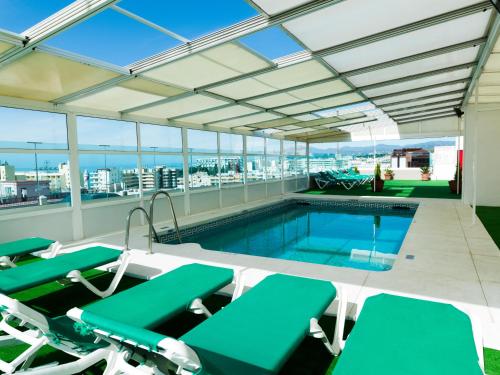 a pool on the roof of a building with chairs and a swimming pool at Hotel Monarque El Rodeo in Marbella