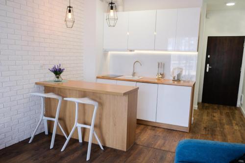 a kitchen with a counter with two stools and a sink at Apartment & Room MARINA BORKI - Apartamenty ZEFIR in Augustów