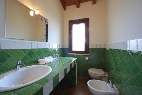 a green bathroom with a sink and a toilet at Casale Madeccia in Sonnino