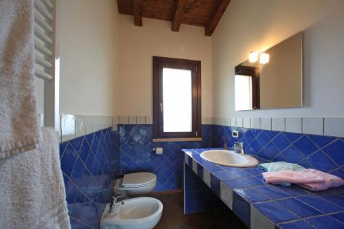 a blue tiled bathroom with a sink and a toilet at Casale Madeccia in Sonnino