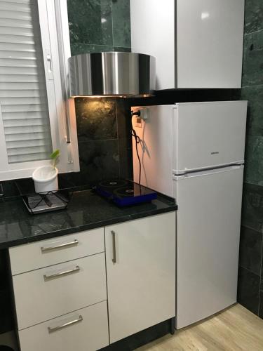 cocina con armarios blancos y nevera en Apartamento Atrapasueños, en Cáceres