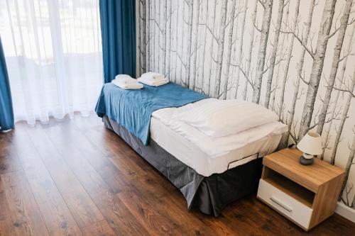1 dormitorio con 1 cama y una pared con árboles en Apartamenty ZEFIR - MARINA BORKI, en Augustów