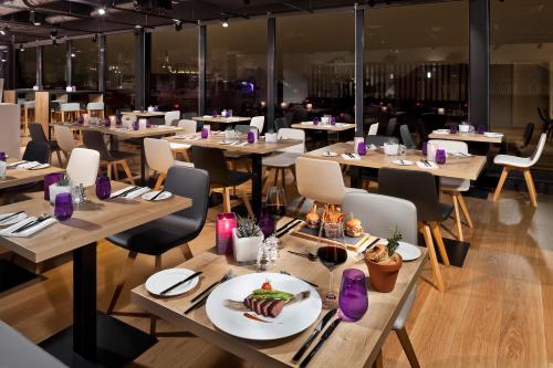 a restaurant with tables and chairs with a plate of food at INNSiDE by Meliá Aachen in Aachen
