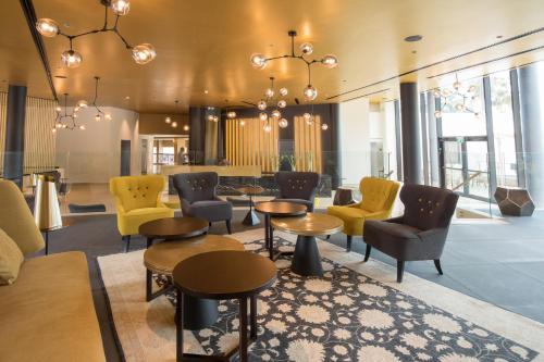 a lobby with yellow chairs and tables at Hotel Lake House Kinneret in Tiberias