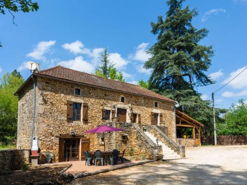 una casa in pietra con un ombrello viola davanti di Beautiful holiday home with private pool a Saint-Cernin-de-lʼHerm