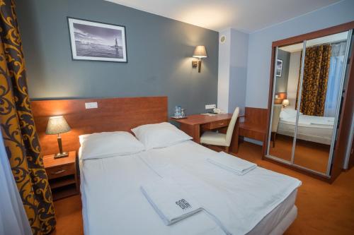 sypialnia z łóżkiem, biurkiem i lustrem w obiekcie Hotel Gordon w Warszawie