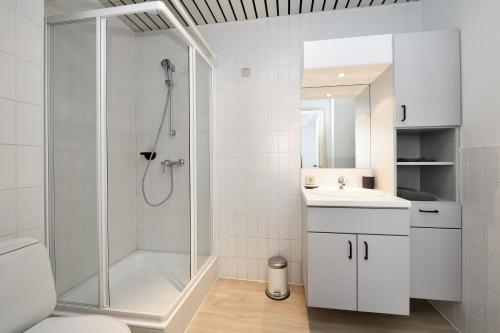 uma casa de banho branca com um chuveiro e um lavatório. em House 22 em Kortrijk